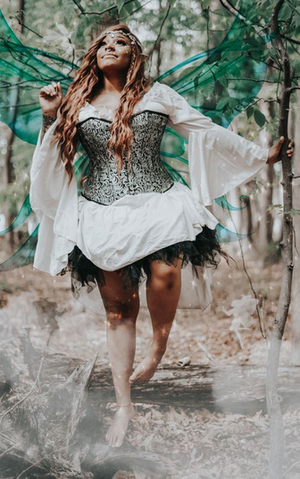 Person dressed as a fairy with blue wings standing looking up at the sky with bright eyes.