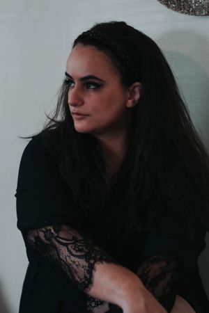 Girl sitting looking off to the left with a black lace dress on