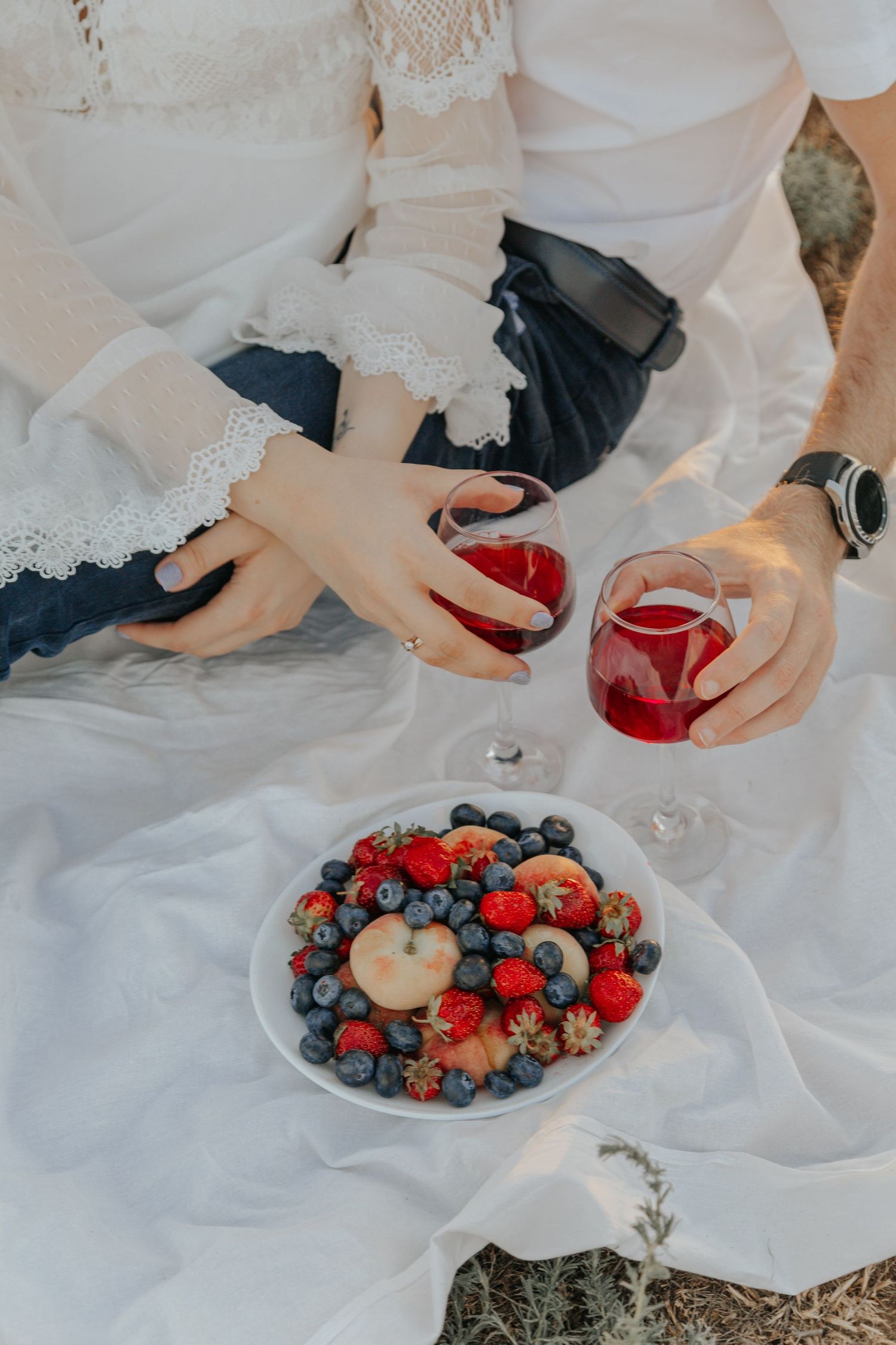 Couple having while and fruit at a picnic for their wedding day.